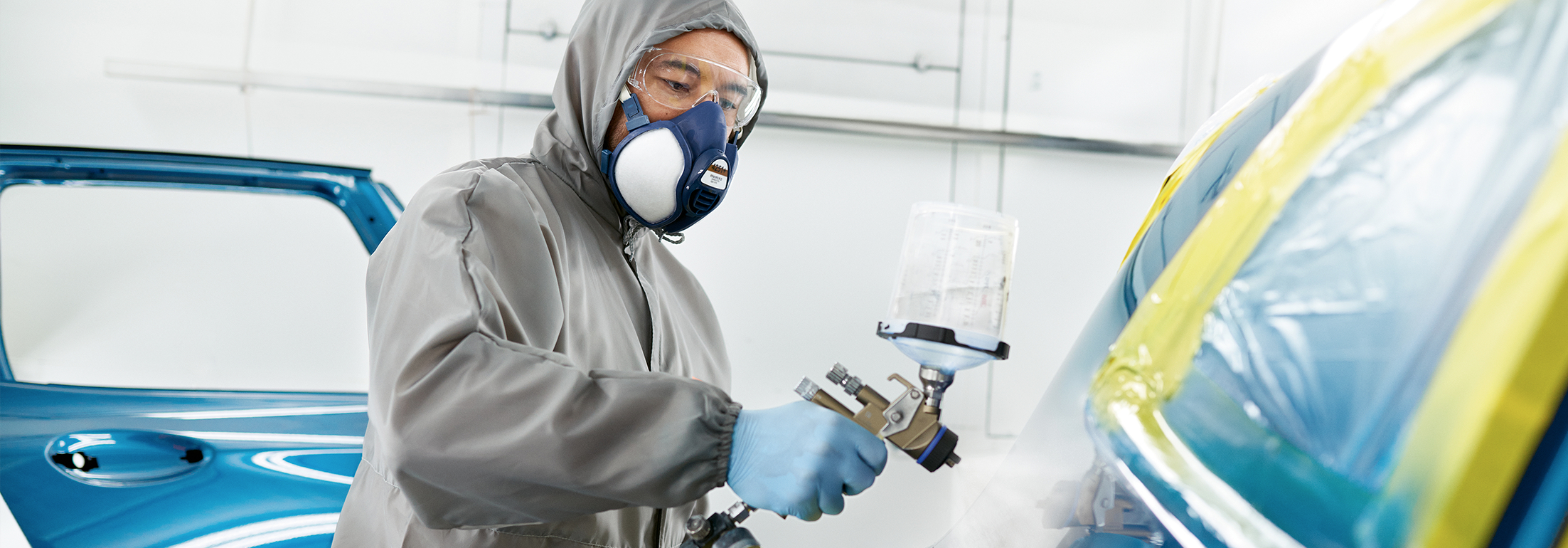 BMW Trained Technician wearing protective gear performs paint work on a BMW vehicle in a BMW Certified Collision Repair Center.